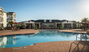 Alternate daytime view clubhouse facing large resort-style swimming pool with gated enclosure